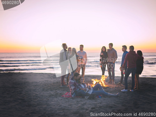 Image of Couple enjoying with friends at sunset on the beach