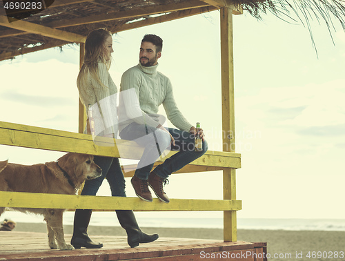 Image of young couple drinking beer together at the beach