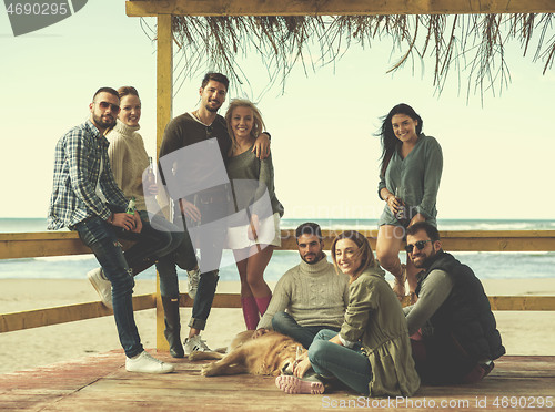 Image of Group of friends having fun on autumn day at beach