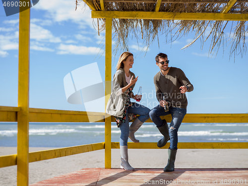 Image of young couple drinking beer together at the beach