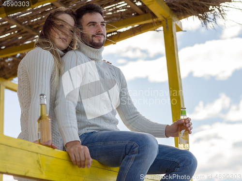 Image of young couple drinking beer together at the beach