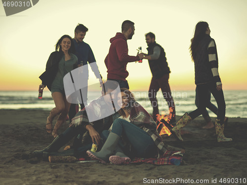 Image of Couple enjoying with friends at sunset on the beach