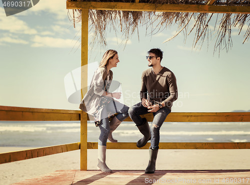 Image of young couple drinking beer together at the beach