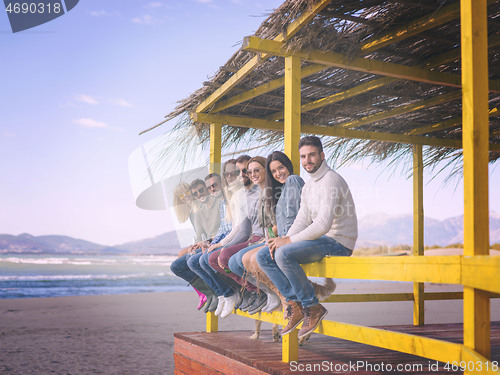 Image of Group of friends having fun on autumn day at beach