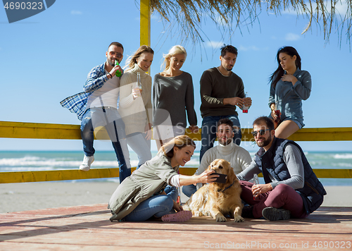 Image of Group of friends having fun on autumn day at beach