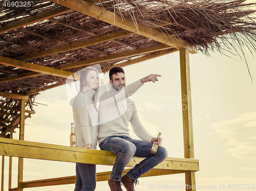 Image of young couple drinking beer together at the beach