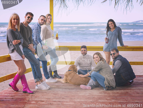 Image of Group of friends having fun on autumn day at beach