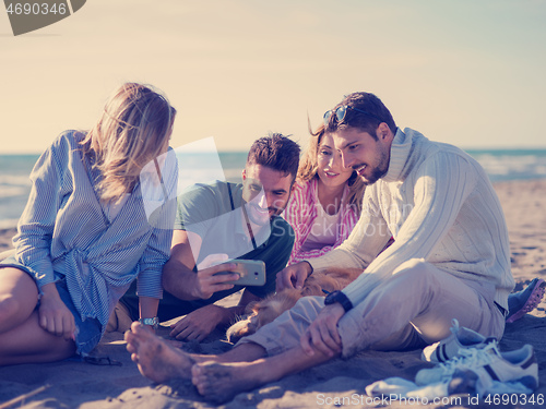 Image of Group of friends having fun on beach during autumn day