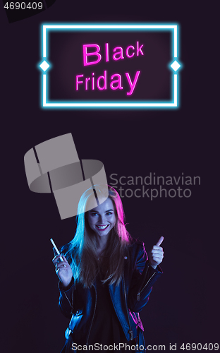 Image of Beautiful woman inviting for shopping in black friday, sales concept. Vertical flyer, neoned style, dark background