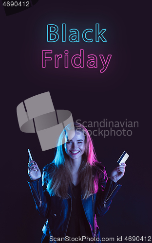 Image of Beautiful woman inviting for shopping in black friday, sales concept. Vertical flyer, neoned style, dark background