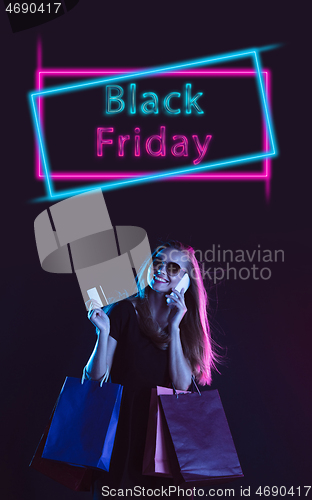 Image of Beautiful woman inviting for shopping in black friday, sales concept. Vertical flyer, neoned style, dark background