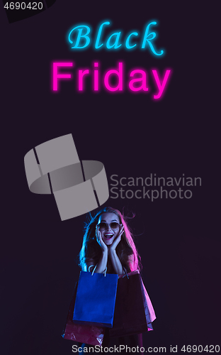 Image of Beautiful woman inviting for shopping in black friday, sales concept. Vertical flyer, neoned style, dark background