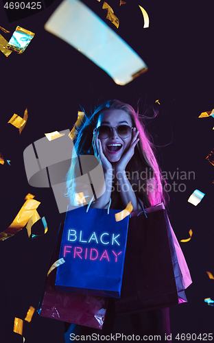 Image of Beautiful woman inviting for shopping in black friday, sales concept. Vertical flyer, neoned style, dark background