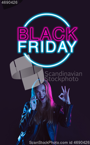 Image of Beautiful woman inviting for shopping in black friday, sales concept. Vertical flyer, neoned style, dark background