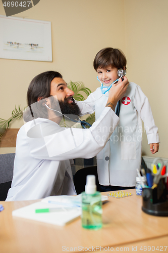 Image of Paediatrician doctor examining a child while wearing face mask in comfortabe medical office