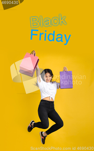 Image of Beautiful woman inviting for shopping in black friday, sales concept. Vertical flyer, yellow background