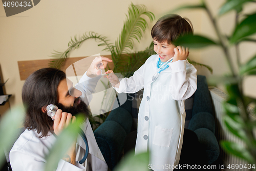 Image of Paediatrician doctor examining a child while wearing face mask in comfortabe medical office