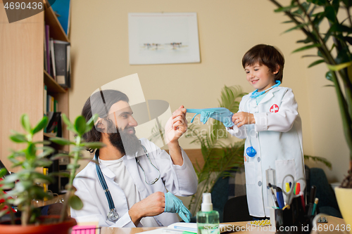 Image of Paediatrician doctor examining a child while wearing face mask in comfortabe medical office