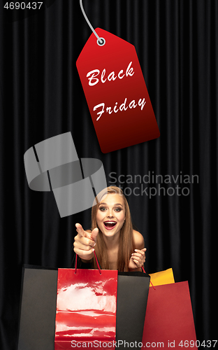 Image of Beautiful woman inviting for shopping in black friday, sales concept. Vertical flyer, dark background