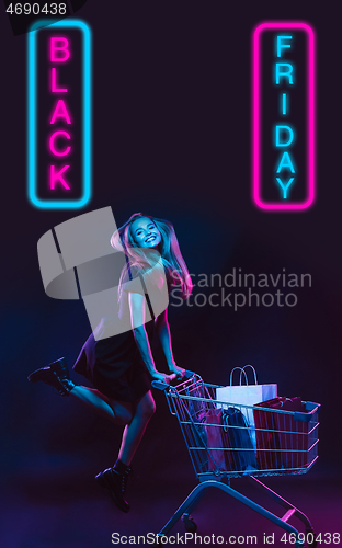 Image of Beautiful woman inviting for shopping in black friday, sales concept. Vertical flyer, neoned style, dark background