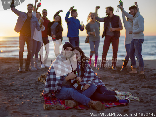 Image of Couple enjoying with friends at sunset on the beach