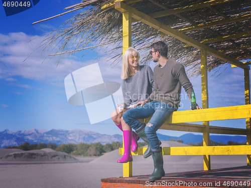 Image of young couple drinking beer together at the beach