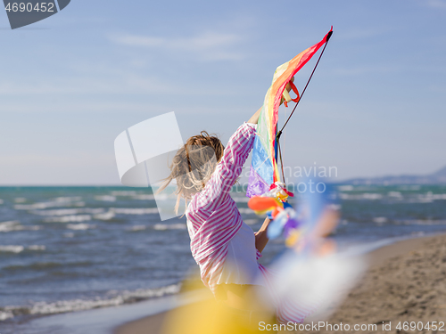 Image of Young Woman holding kite at beach on autumn day