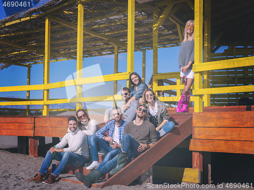 Image of Group of friends having fun on autumn day at beach