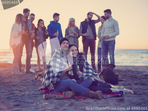 Image of Couple enjoying with friends at sunset on the beach