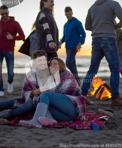 Image of Couple enjoying with friends at sunset on the beach