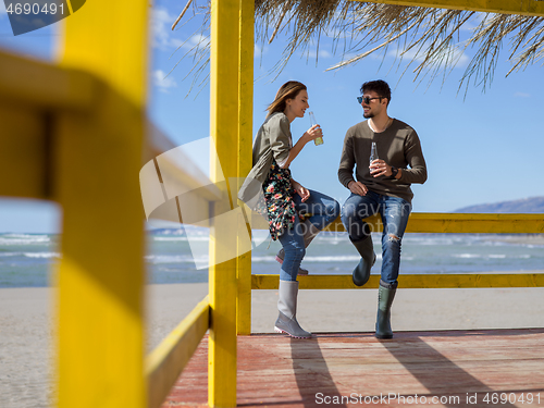 Image of young couple drinking beer together at the beach