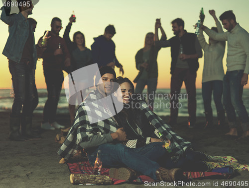 Image of Couple enjoying with friends at sunset on the beach