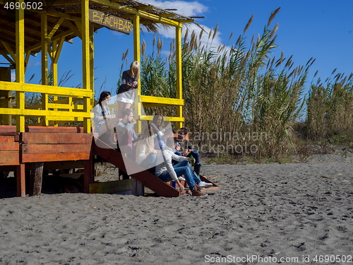 Image of Group of friends having fun on autumn day at beach