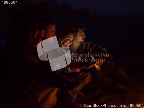 Image of Couple enjoying with friends at night on the beach