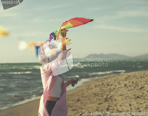 Image of Young Woman holding kite at beach on autumn day