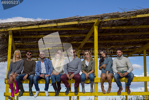 Image of Group of friends having fun on autumn day at beach