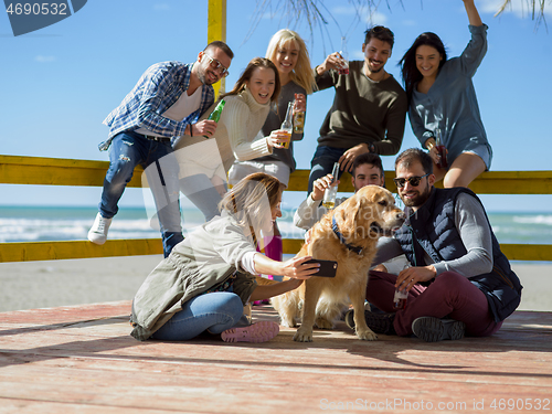 Image of Group of friends having fun on autumn day at beach