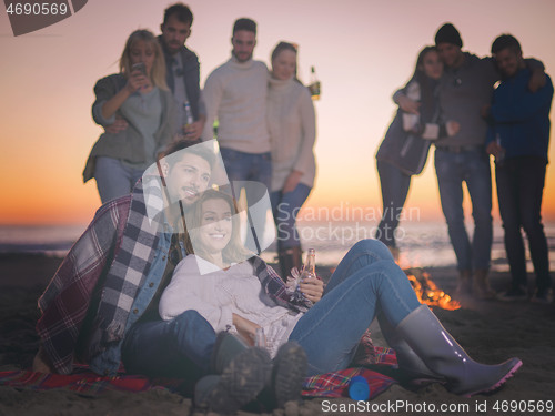 Image of Couple enjoying with friends at sunset on the beach