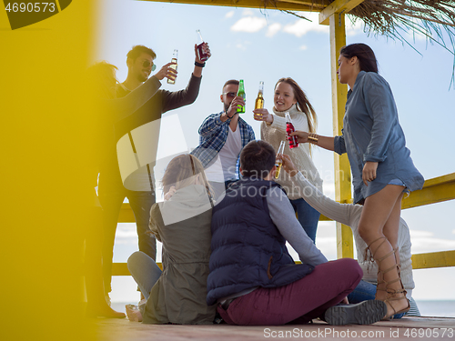 Image of Group of friends having fun on autumn day at beach