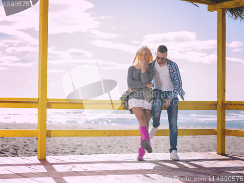 Image of young couple drinking beer together at the beach