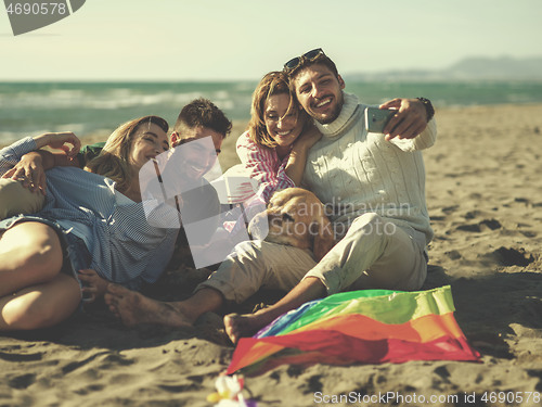 Image of Group of friends having fun on beach during autumn day