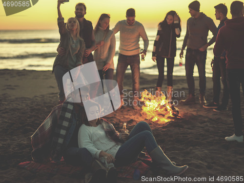 Image of Couple enjoying with friends at sunset on the beach