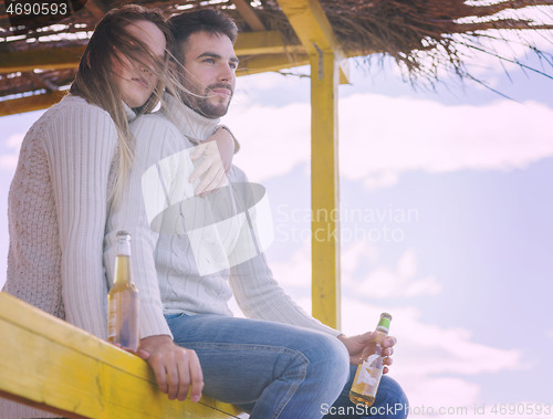 Image of young couple drinking beer together at the beach