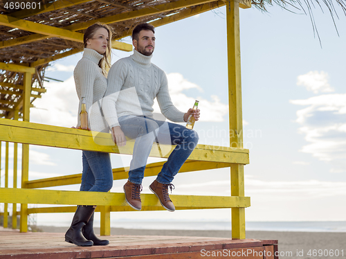 Image of young couple drinking beer together at the beach