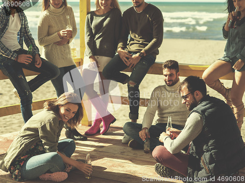 Image of Group of friends having fun on autumn day at beach