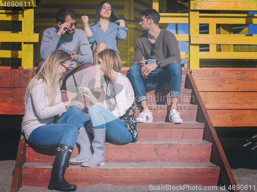 Image of Group of friends having fun on autumn day at beach