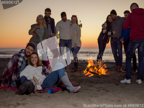 Image of Couple enjoying with friends at sunset on the beach