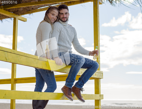 Image of young couple drinking beer together at the beach