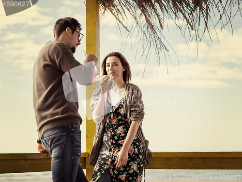 Image of young couple drinking beer together at the beach
