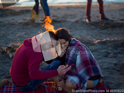 Image of Couple enjoying bonfire with friends on beach